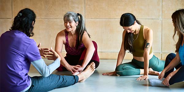 An female student and an instructor have a nice conversation during an adult yoga class.
